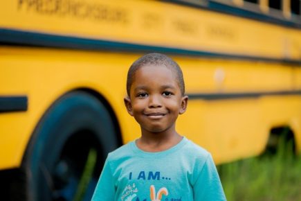 Black boy in front of schoolbus