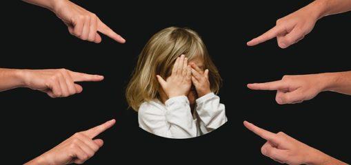 Young girl with 6 hands pointing at her and hands over eyes