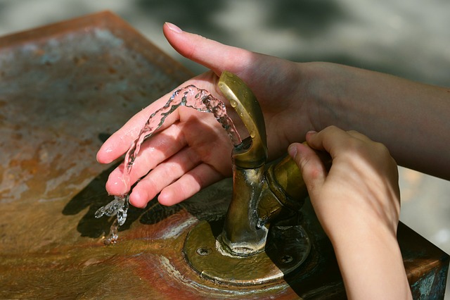 Two young hands in water fountain