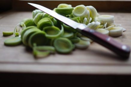 Knife with chopped vegetables on cutting board