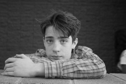 Tween male, black and white photo, leaning on table