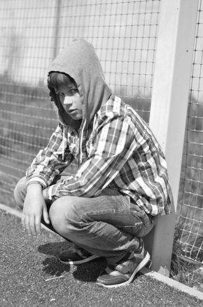 Tween crouching, black and white picture, hoodie on head