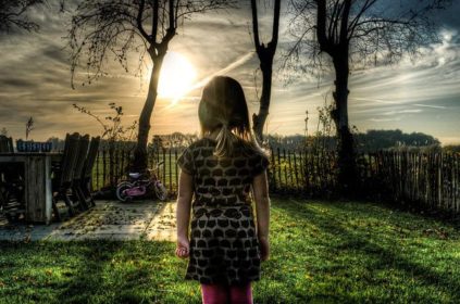 Girl looking at bike with sun setting in yard