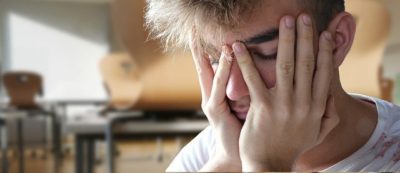 Male teenage student with hands on face