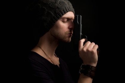 Student profile with gun next to face pointing upward