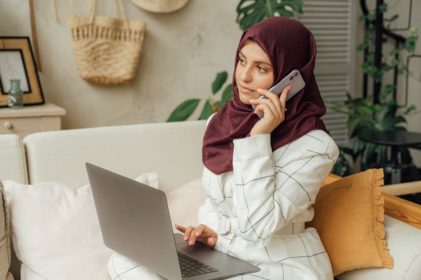 Muslim woman on phone to school with computer