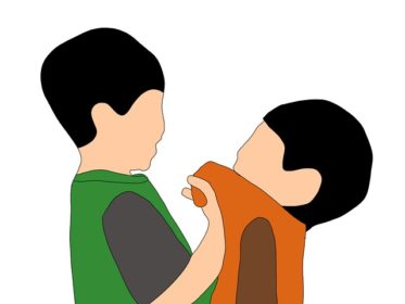Boy picking up other boy by shirt