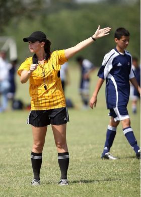 Female soccer referee for high school pointing left arm