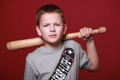 Young boy holding baseball bat with mean expression