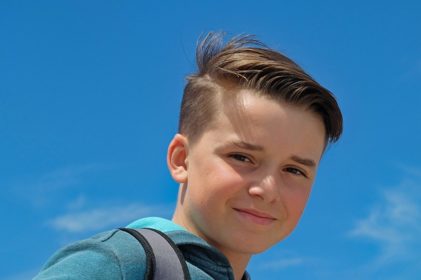 Boy looking at camera with backpack strap over right shoulder