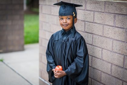 Black young male student in graduation cap and robe