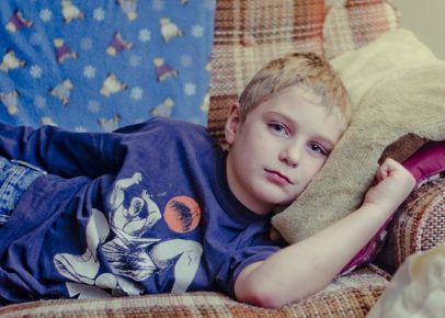 Sad young boy laying on couch