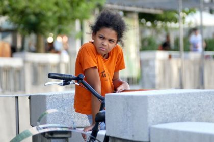 Black child sitting on bike glaring