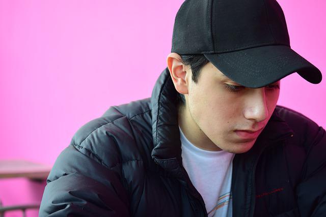 Male teen with black hat looking down