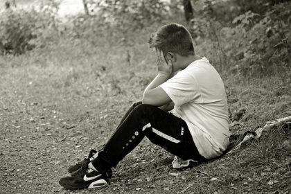 Boy sitting down with hand on face, black and white photo