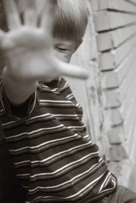 Young boy with hand up blocking camera