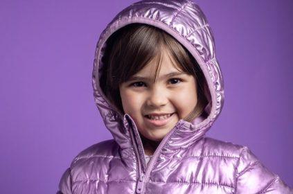 Young girl in purple shiny hood with purple background