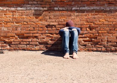 Teen sitting on ground with head on legs