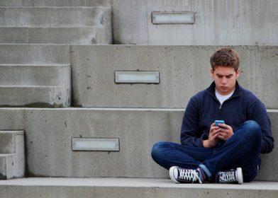 Male teen sitting looking at phone