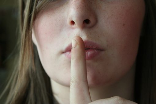 Girl with finger in front of mouth secret