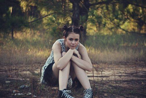 Teen girl sitting on grass head on knees