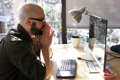 Man looking at computer screen, confused, side view