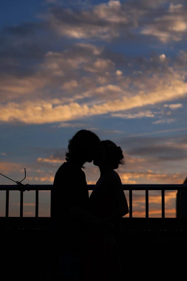 Picture of male female kissing in sunset, figures are dark due to shadow