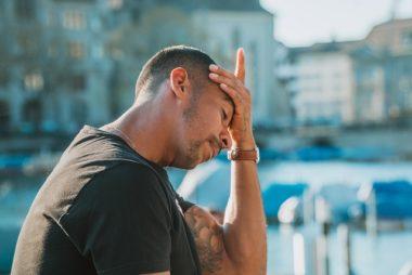 Male parent with hand on head and tattoos