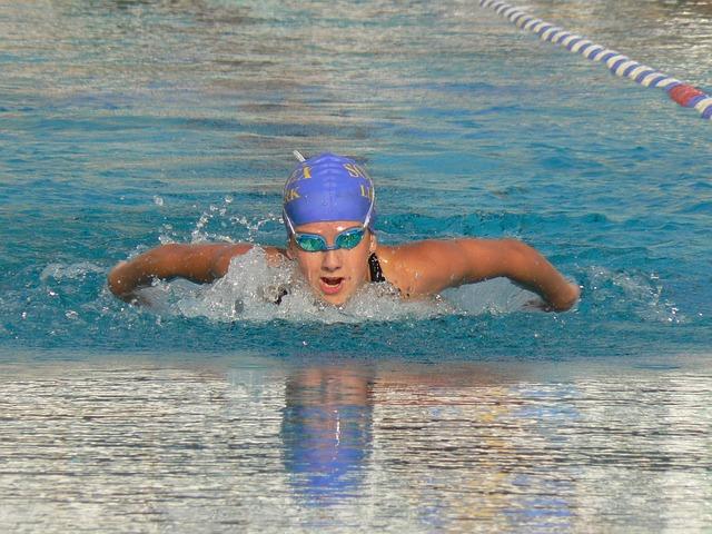 Female teen swimmer competing in water