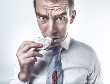 Man chewing on rice cake in suit and tie with eyebrows raised