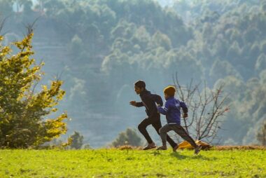 Two kids running across a field, right to left