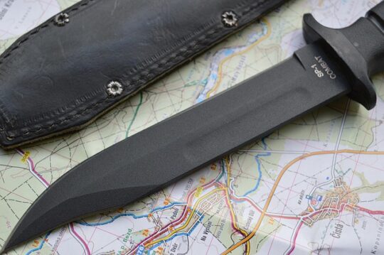 Black knife laying down, with sheath, on a map