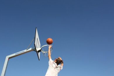 Person shooting basket in basketball hoop